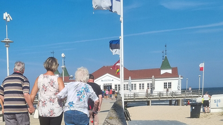 Pflegekraft mit Bewohner und Bewohnerin auf der Seebrücke