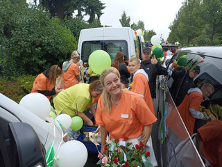 Eine Pflegekraft mit Blumen und Luftballons blickt lächelnd in die Kamera beim Festumzug zum Jubiläums-Müritzfest mit Pflegekräften, Bewohnerinnen und Bewohnern aus dem Immanuel Haus Ecktannen