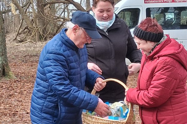 Seniorinnen und Senioren aus der Tagespflege bei einem Osterspaziergang im Wald mit gefülltem Osterkörbchen