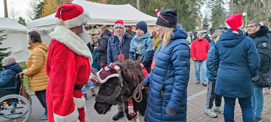 Ein Kind begleitet von einer Frau beim Ponyreiten mit dem Weihnachtsmann beim Weihnachtsmarkt des Immanuel Haus Ecktannen Ein Kind begleitet von einer Frau beim Ponyreiten mit dem Weihnachtsmann beim Weihnachtsmarkt des Immanuel Haus Ecktannen