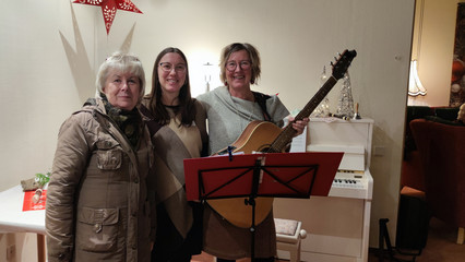 Drei Frauen vor einem Notenständer mit einer Gitarre beim Weihnachtsmarkt des Immanuel Haus Ecktannen Drei Frauen vor einem Notenständer mit einer Gitarre beim Weihnachtsmarkt des Immanuel Haus Ecktannen