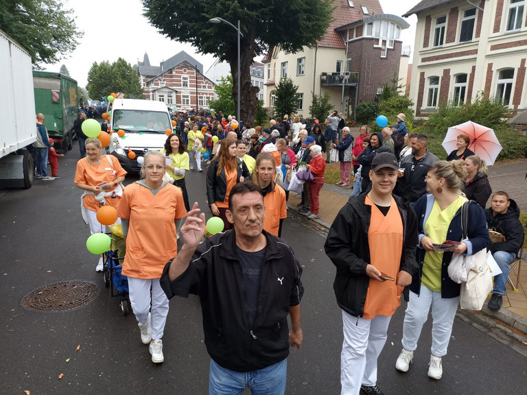 Mitarbeitende auch in Funktionskleidung laufen vor dem Transporter beim Festumzug zum Jubiläums-Müritzfest mit Pflegekräften, Bewohnerinnen und Bewohnern aus dem Immanuel Haus Ecktannen Mitarbeitende auch in Funktionskleidung laufen vor dem Transporter beim Festumzug zum Jubiläums-Müritzfest mit Pflegekräften, Bewohnerinnen und Bewohnern aus dem Immanuel Haus Ecktannen